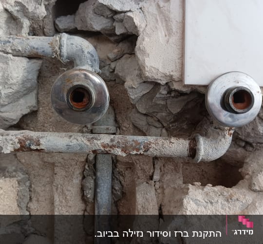 צינורות חלודים בקיר עם חיבורים מתכתיים